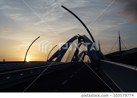 A person crossing the bridge in the morning glow 103579774