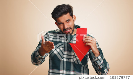 Upset indian man showing red arrow pointing down, concept of downgrade bankruptcy money fail, fall Upset indian man showing red arrow pointing down, concept of downgrade bankruptcy money fail, fall 103579777