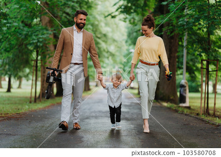 Young family with little son on walk after work. Young family with little son on walk after work. 103580708