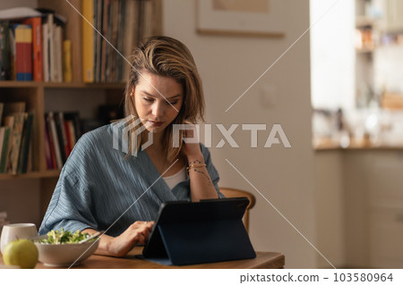 Portrait of young woman in her apartment working on laptop. Portrait of young woman in her apartment working on laptop. 103580964