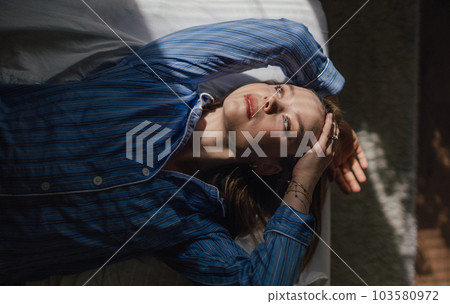 Top view of woman lying in her bed, morning sun shining on her face. 103580972