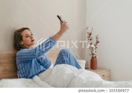 Young happy woman taking selfie in her bed. Young happy woman taking selfie in her bed. 103580977