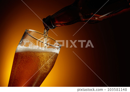 Pouring beer from a bottle into a glass. Pouring beer from a bottle into a glass. 103581148