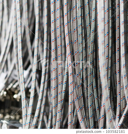 Closed up braided stainless steel texture of flexible hose arranged in a row against white wall. Closed up braided stainless steel texture of flexible hose arranged in a row against white wall. 103582181