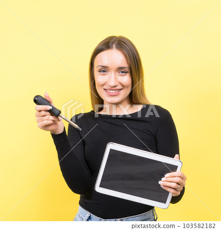 Service center. Laptop Repair. Female screwdriver unscrews laptop bolts on yellow background Service center. Laptop Repair. Female screwdriver unscrews laptop bolts on yellow background 103582182