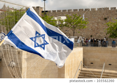 Israeli flag fluttered in the wind with the walls of the old city in the background, 103582260