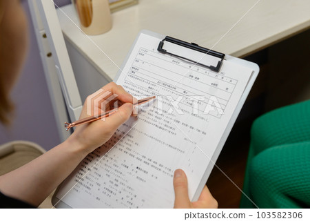 A woman's hand writing in a medical record (medical questionnaire) left-handed counseling beauty salon A woman's hand writing in a medical record (medical questionnaire) left-handed counseling beauty salon 103582306