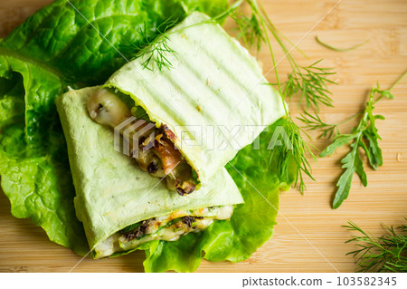 green hot vegetarian pita bread with mushrooms and different vegetables, with lettuce leaves . green hot vegetarian pita bread with mushrooms and different vegetables, with lettuce leaves . 103582345
