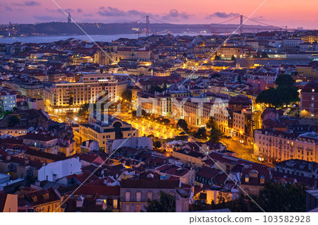 Evening aerial view of Lisbon famous view from Miradouro da Senhora do Monte tourist viewpoint of Alfama and Mauraria old city districts, 25th of April Bridge in the evening twilight. Lisbon, Portugal Evening aerial view of Lisbon famous view from Miradouro da Senhora do Monte tourist viewpoint of Alfama and Mauraria old city districts, 25th of April Bridge in the evening twilight. Lisbon, Portugal 103582928