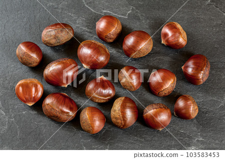 Flat lay photo, chestnuts on black slate board. 103583453