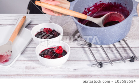Step by step. Serving homemade mix berry compote in small white bowls on a wooden table. 103583584