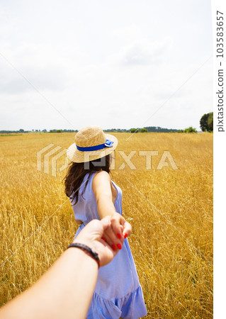 a girl in a blue dress is standing with her back in a wheat field 103583657