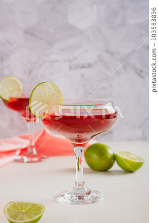 Cosmopolitan cocktail with lime in glasses on the table vertical view 103583836