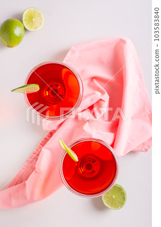 Alcoholic cosmopolitan cocktail in glasses and lime on the table top and vertical view Alcoholic cosmopolitan cocktail in glasses and lime on the table top and vertical view 103583840