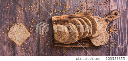 Pieces of homemade buckwheat bread on a cutting board on the table top view web banner 103583855