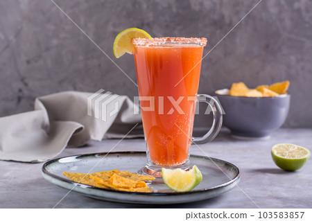 Michelada cocktail with tomato juice, beer and lime in a glass and nachos Michelada cocktail with tomato juice, beer and lime in a glass and nachos 103583857