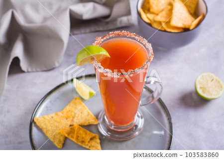 Michelagua mocktail with tomato juice and lime juice in a glass and nachos in a bowl Michelagua mocktail with tomato juice and lime juice in a glass and nachos in a bowl 103583860