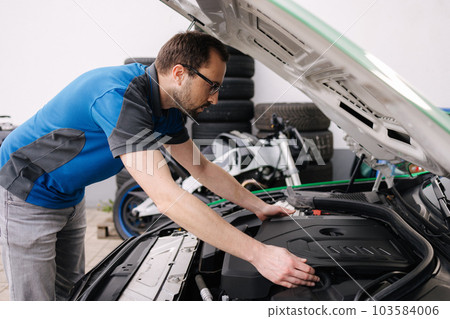Male mechanic examining and maintenance to customer the engine. Open vehicle car hood. Safety inspection test engine. Transportation repair service concept 103584006