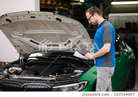 Handsome car mechanic detailed vehicle inspection. Auto service concept Handsome car mechanic detailed vehicle inspection. Auto service concept 103584007