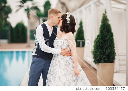 Beautiful bride and groom embracing and kissing on their wedding day 103584457
