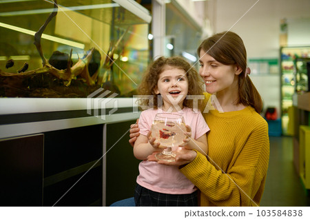 Portrait of happy mother and little daughter bought fish at pet shop Portrait of happy mother and little daughter bought fish at pet shop 103584838