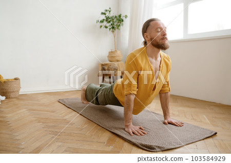 Young athletic man standing in Urdhva Mukha Svanasana yoga pose 103584929
