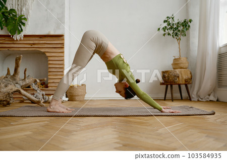 Young slim woman standing in Adho Mukha Svanasana yoga position 103584935