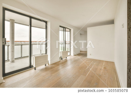 an empty living room with wood flooring and sliding glass doors looking out onto the water view from the balcony an empty living room with wood flooring and sliding glass doors looking out onto the water view from the balcony 103585078