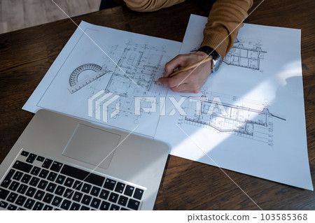 Unrecognizable male architect sketching construction project with laptop drawings drawing blueprint Unrecognizable male architect sketching construction project with laptop drawings drawing blueprint 103585368