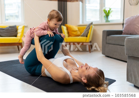 Young sporty mother and baby girl working out exercising together at home. Young sporty mother and baby girl working out exercising together at home. 103585568