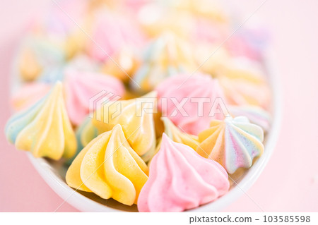 Multicolored unicorn meringue cookies on a white serving plate. 103585598