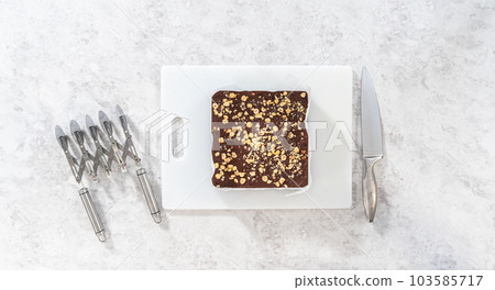 Flat lay. Scoring chocolate hazelnut fudge using a wheel dough cutter for cutting into small square pieces. Flat lay. Scoring chocolate hazelnut fudge using a wheel dough cutter for cutting into small square pieces. 103585717