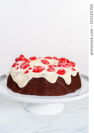 Freshly baked red velvet bundt cake with chocolate lips and hearts over cream cheese glaze for Valentine's Day. 103585769