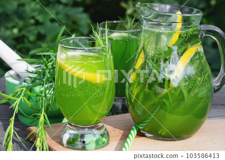 Homemade summer refreshing tarragon lemon drink on patio table 103586413