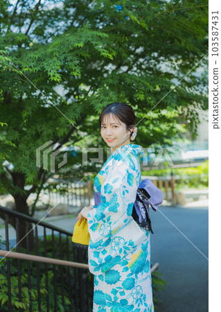 A woman in a yukata walking outdoors 103587431