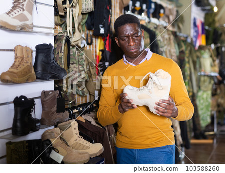 African american man chooses hiking boots at travel store African american man chooses hiking boots at travel store 103588260