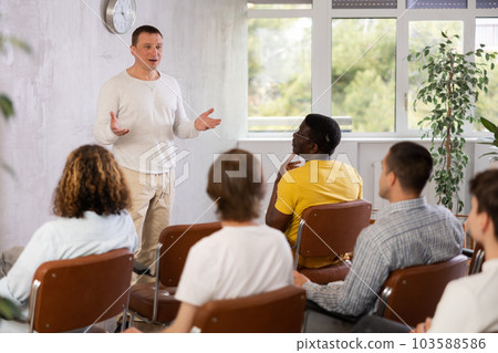 Middle-aged man teacher reading lecture for a group of guys Middle-aged man teacher reading lecture for a group of guys 103588586