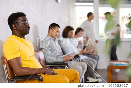 Middle-aged male visitor sitting on chair in waiting hall of clinic Middle-aged male visitor sitting on chair in waiting hall of clinic 103588617