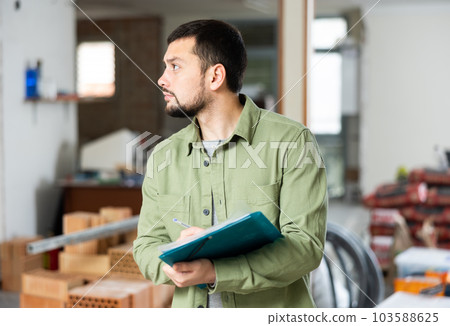 Architect making notes on indoor construction site 103588625