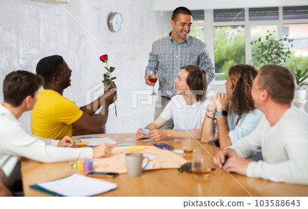 Gay african american man gifting flower to partner in presence of friends Gay african american man gifting flower to partner in presence of friends 103588643
