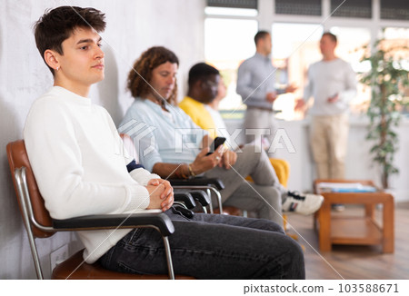 Young guy waiting for appointment with doctor in lobby Young guy waiting for appointment with doctor in lobby 103588671