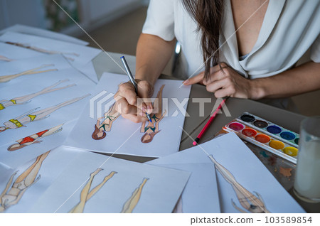 Faceless woman draws sketches of swimwear. Close-up of the hands of a fashion designer. 103589854