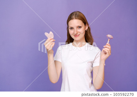 Young lady massaging her face by Gua Sha Quartz Stone Scraper for skin care 103592270