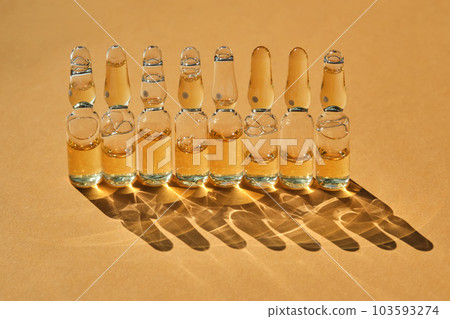 Glass ampoules on a beige orange background. Glass ampoules on a beige orange background. 103593274