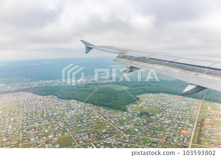 View of airplane wing, blue skies and green land during landing. Airplane window view. 103593802