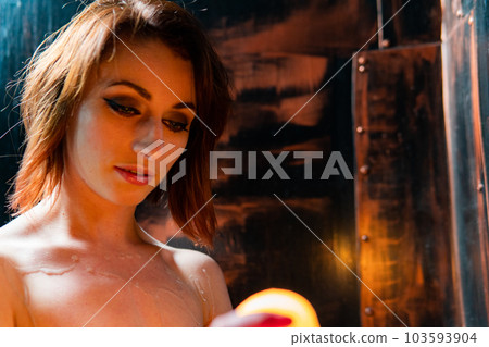 Body scape of a well-shaped woman with a burning candle and wax on her bum 103593904