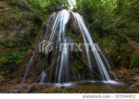 A waterfall in a mountain forest 103594952