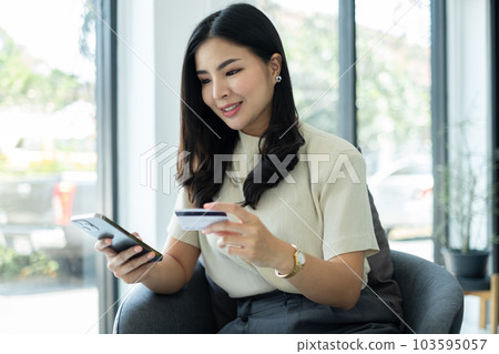Asian girl shopping online holding credit and using smartphone enter their card number in the mobile phone app to purchase and payment in internet store 103595057