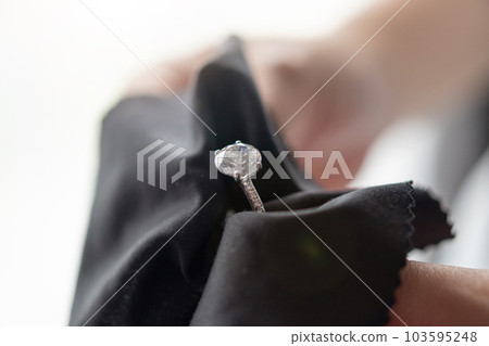 Jeweller cleaning jewelry diamond ring with fabric cloth Jeweller cleaning jewelry diamond ring with fabric cloth 103595248