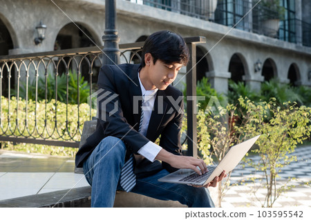 Experienced businessman. picture of a businessman. Asian businessmen sit looking laptop in front of modern office buildings 103595542